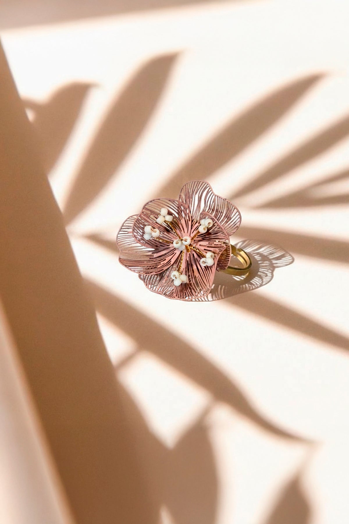 detalle de anillo Camélia ajustable acero inoxidable dorado con filigrana rosa